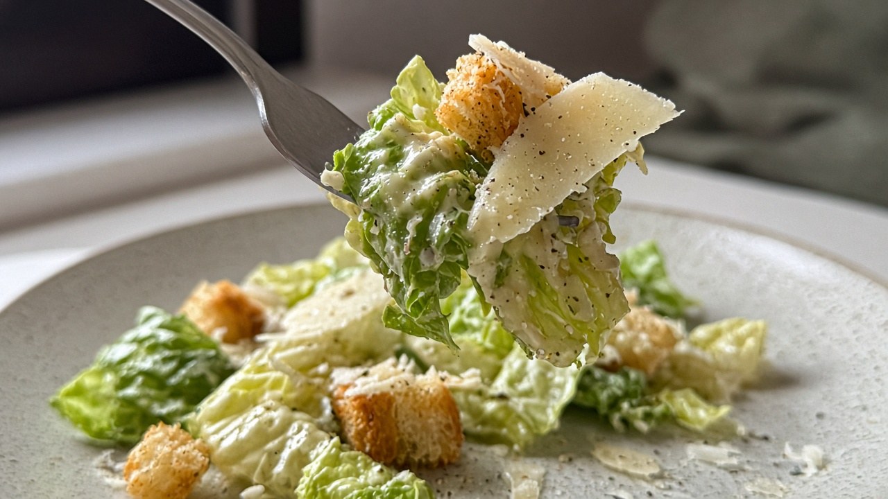 Close-up of Caesar salad with croutons and Parmesan on a fork